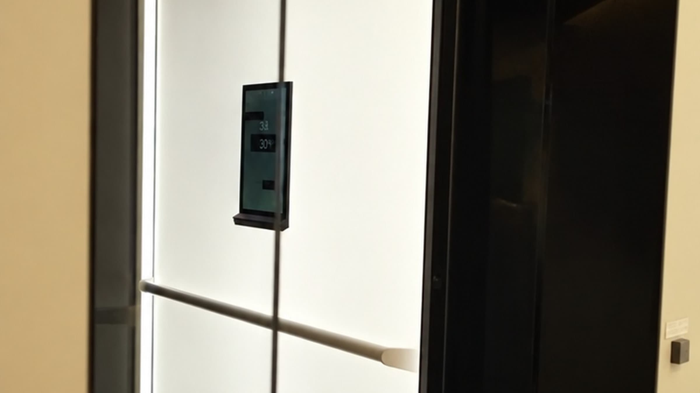 Open glass door looking into a Jet Black Swift Pro XL cabin with Electric Opal white panels and touchscreen, set in a cream wall in a Broadbeach penthouse on the Gold Coast